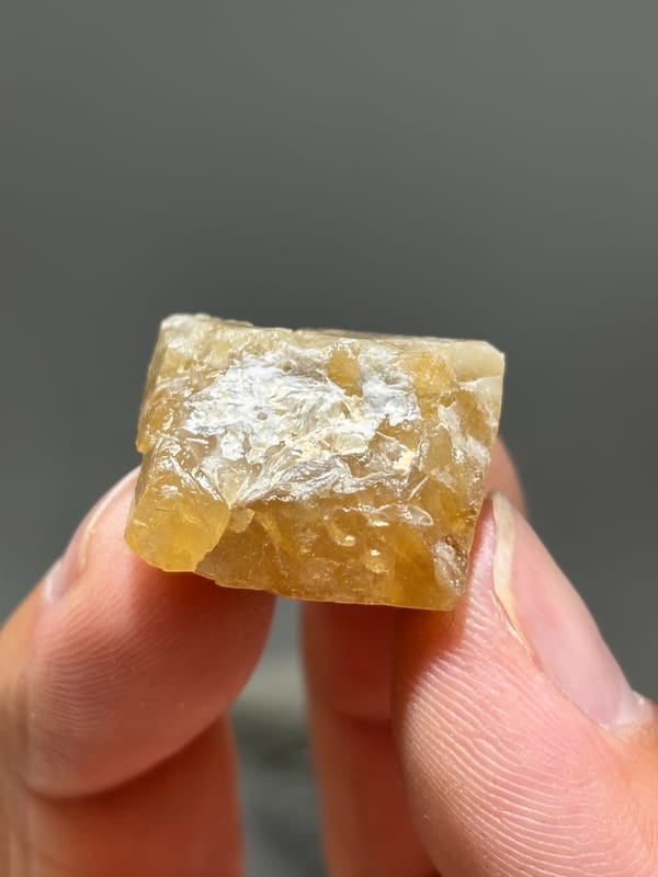 Honey scheelite with frosted top from Xuebaoding, Sichuan, China, held in hand