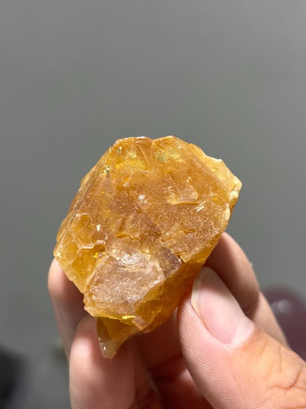 Honey-orange scheelite floater from Xuebaoding, Sichuan, China, held in hand