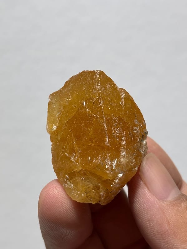 Honey-orange scheelite crystal from Xuebaoding, Sichuan, China, held in hand