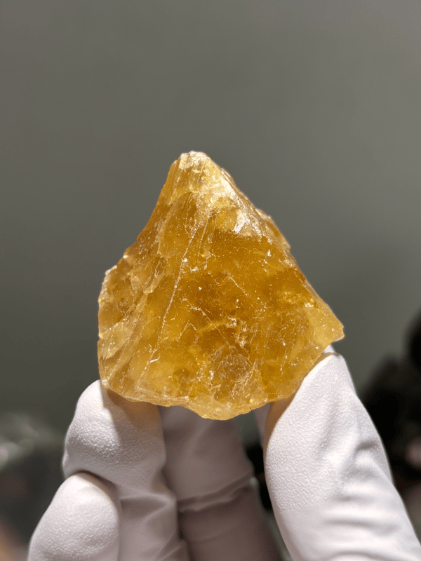 Honey-orange scheelite crystal from Xuebaoding, Sichuan, China, held in gloved hand