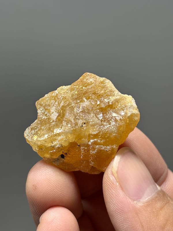 Honey-yellow scheelite crystal from Xuebaoding, Sichuan, China, held in hand