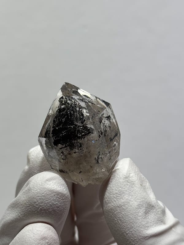 Stout black quartz with floater base from Yunnan, China, held in gloved hand