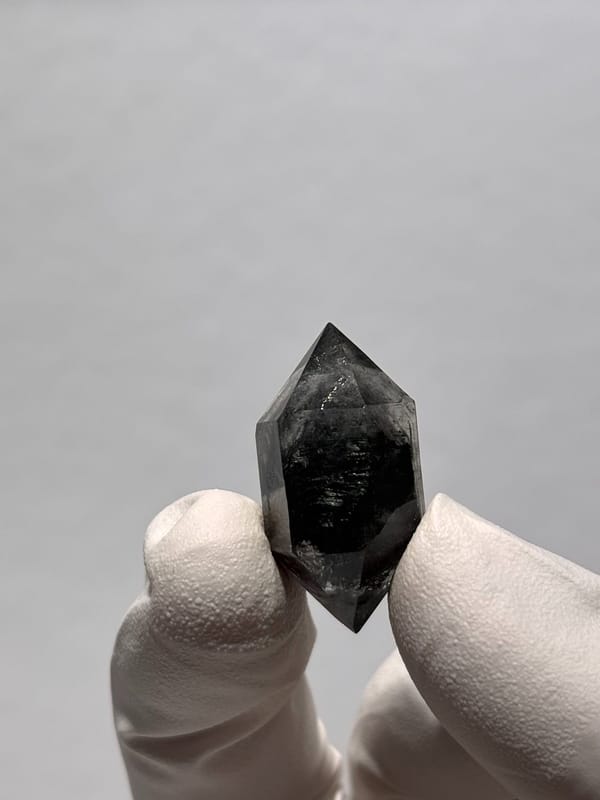 Stout black double-terminated quartz from Yunnan, China, held in gloved hand