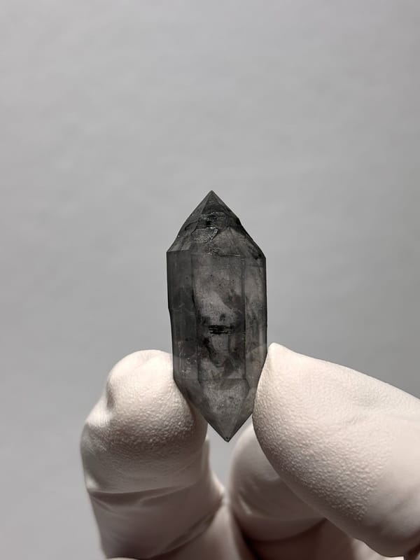 Stout black sketch-pattern double-terminated quartz from Yunnan, China, held in gloved hand