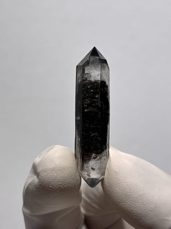 Black sugar-core double-terminated quartz from Yunnan, China, held in gloved hand