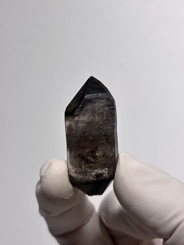 Black-capped double-terminated quartz from Guizhou, China, held in gloved hand