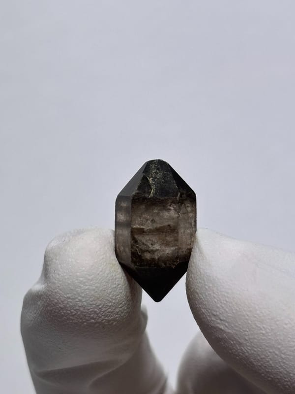 Tiny black-capped double-terminated quartz from Yunnan, China, detail of the matrix contact