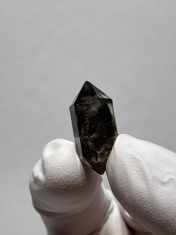 Tiny black-flecked double-terminated quartz from Yunnan, China, close-up of the crystal faces