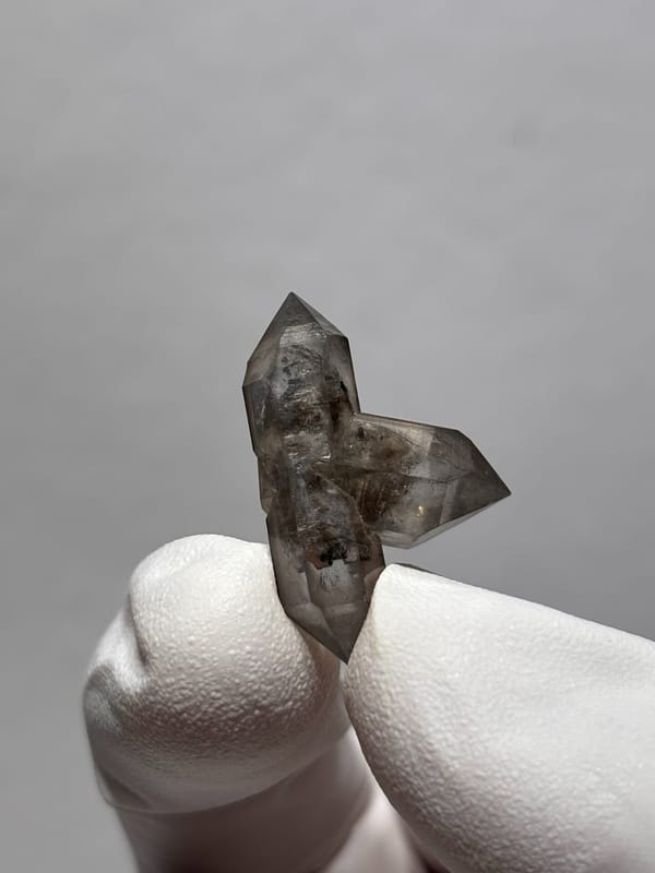 Tiny black-flecked quartz pair with crossing crystal from Yunnan, China, close-up of the crystal faces