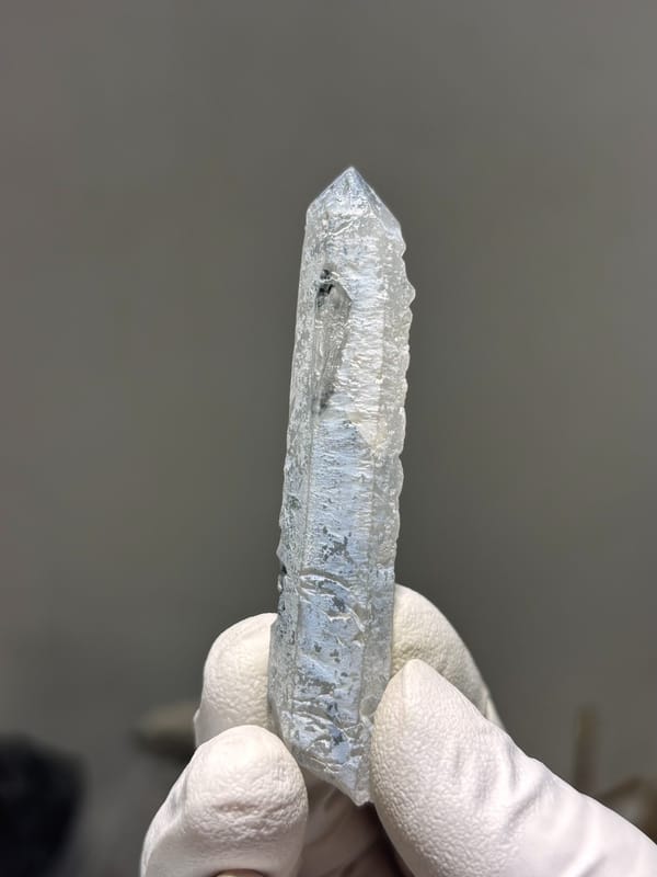 Slender blue-grey quartz wand with complete tip from Inner Mongolia, China, close-up of the crystal faces