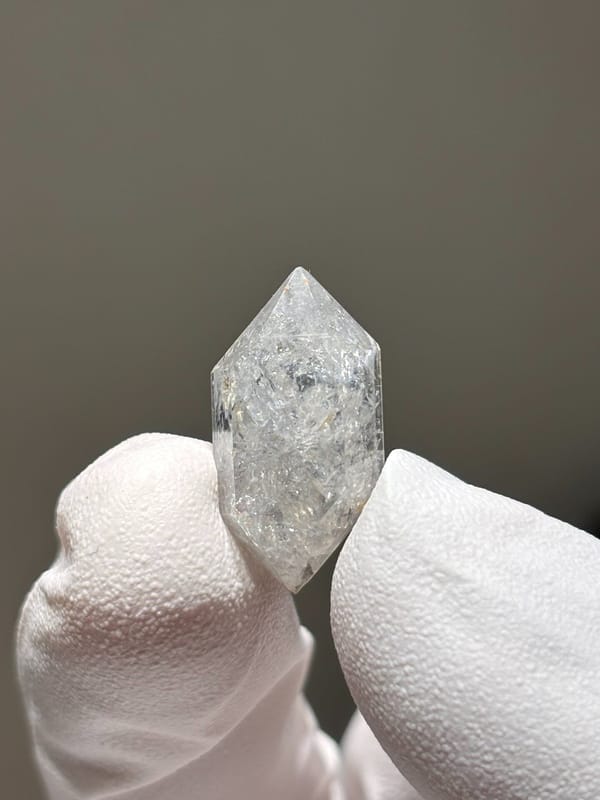 Tiny burst-crystal double-terminated quartz with sparkles from Yunnan, China, held in gloved hand