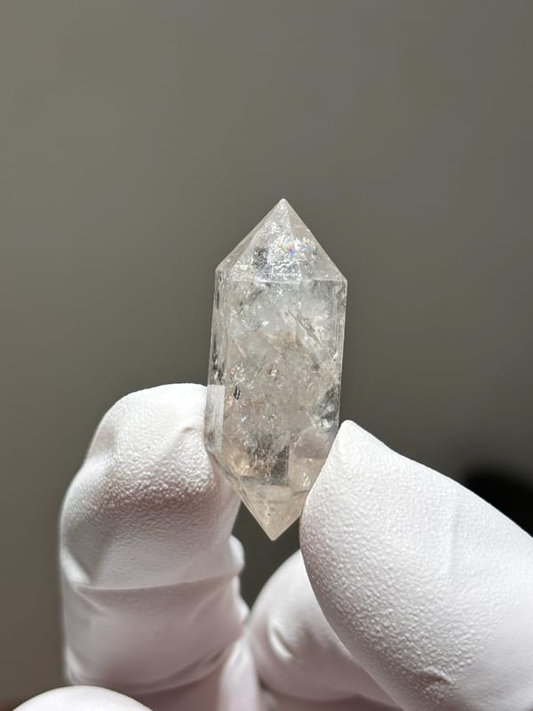 Burst-crystal double-terminated quartz with sparkling flecks from Yunnan, China, held in gloved hand