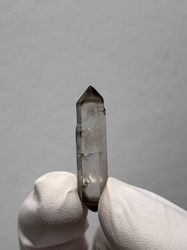 Needle-thin capped double-terminated quartz from Yunnan, China, held in gloved hand