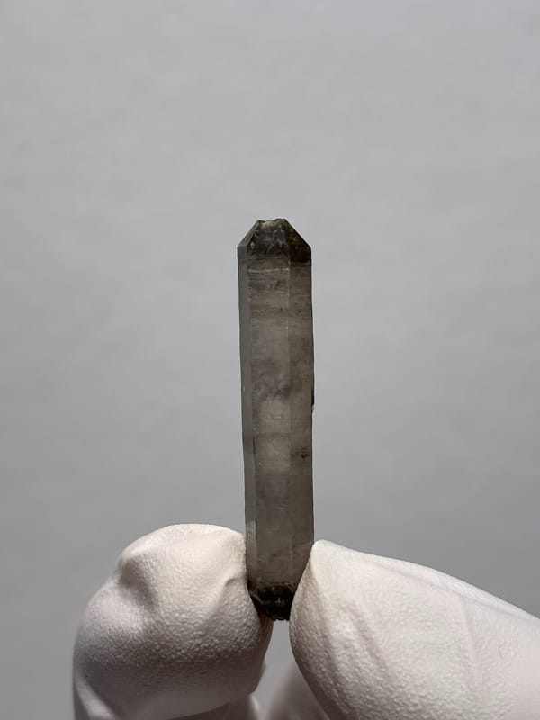 Needle-thin capped double-terminated quartz from Yunnan, China, held in gloved hand