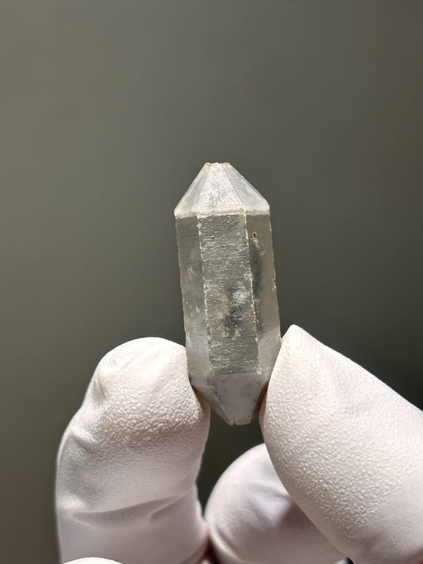 Capped double-terminated quartz with grey phantom from Yunnan, China, held in gloved hand