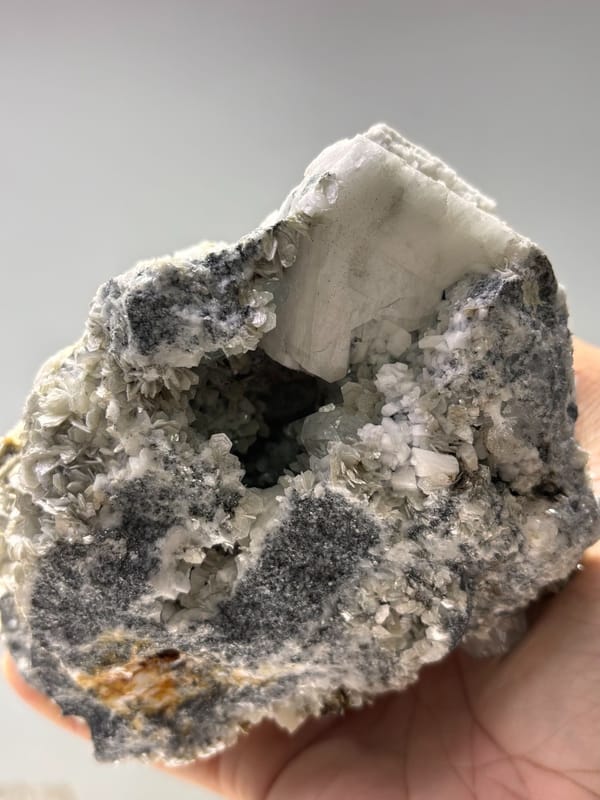 Dark mica block with aquamarine, cassiterite and scheelite from Xuebaoding, Sichuan, China, detail of the matrix contact