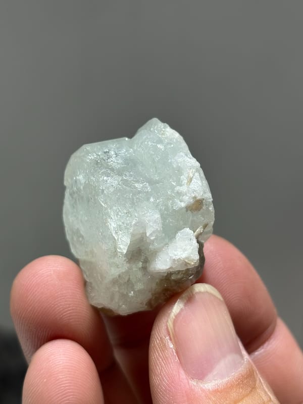 Glassy pale aquamarine with iridescent faces and scheelite from Xuebaoding, Sichuan, China, close-up of the crystal faces