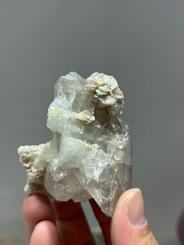 Quartz point over white feldspar with aquamarine and mica from Xuebaoding, Sichuan, China, close-up of the crystal faces