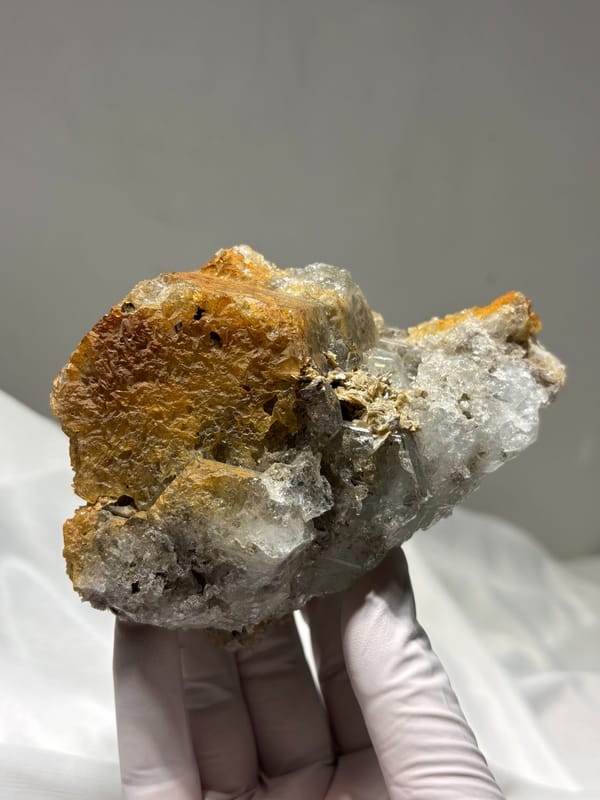 Aquamarine block with rusty matrix from Xuebaoding, Sichuan, China, held in gloved hand