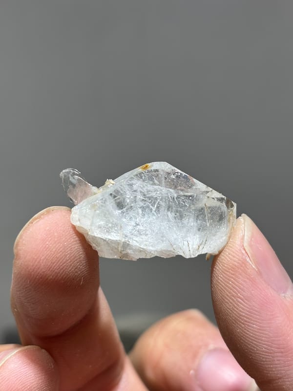 Tiny clear aquamarine sliver with mica from Xuebaoding, Sichuan, China, held in hand