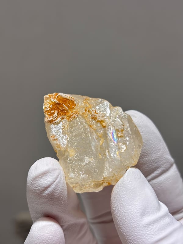 Clear aquamarine with mica and fluorite from Xuebaoding, Sichuan, China, held in gloved hand