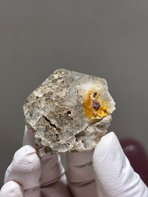 Etched pale aquamarine with clay-filled pocket from Xuebaoding, Sichuan, China, held in gloved hand