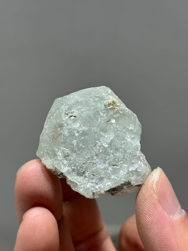 Frosted pale green aquamarine with floater faces from Xuebaoding, Sichuan, China, held in hand