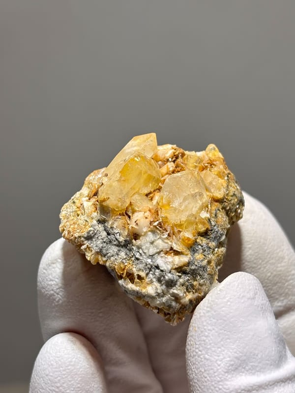 Golden-stained aquamarine on dark mica from Xuebaoding, Sichuan, China, close-up of the crystal faces