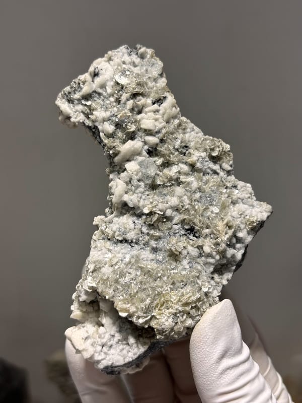 Grey matrix spire with aquamarine, mica and feldspar from Xuebaoding, Sichuan, China, close-up of the crystal faces