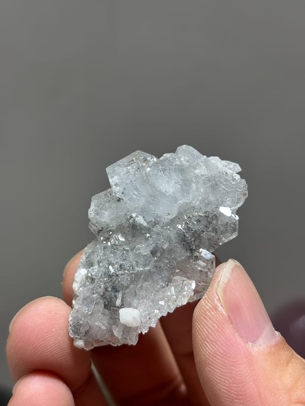 Multi-crystal aquamarine floater with frosted faces from Xuebaoding, Sichuan, China, held in hand