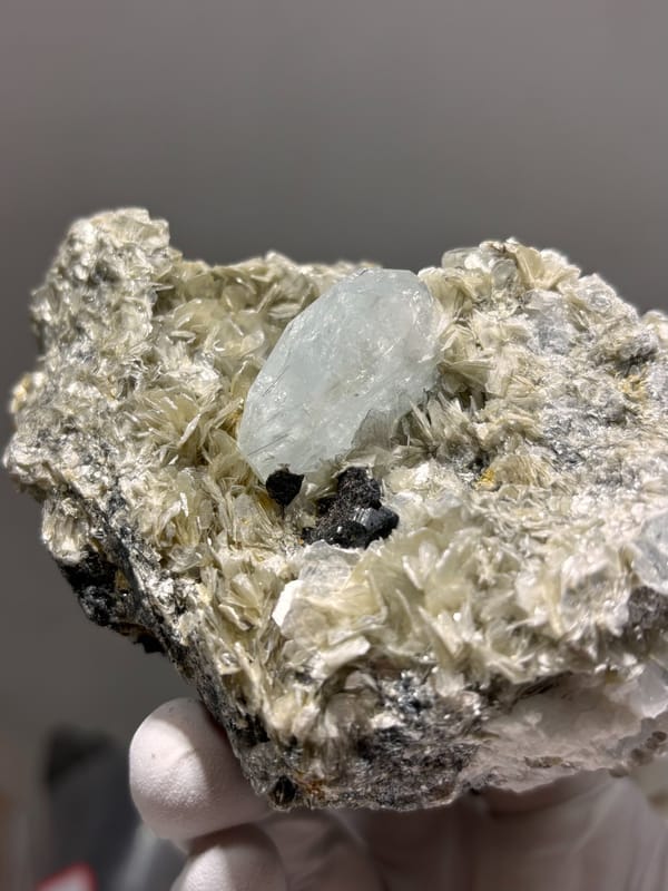Pale aquamarine prism in tan mica with cassiterite from Xuebaoding, Sichuan, China, second angle