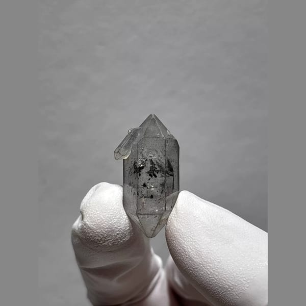 Clear double-terminated Yunnan quartz with dark inclusions — complete view