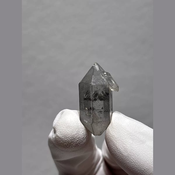 Clear double-terminated Yunnan quartz with dark inclusions — detail view