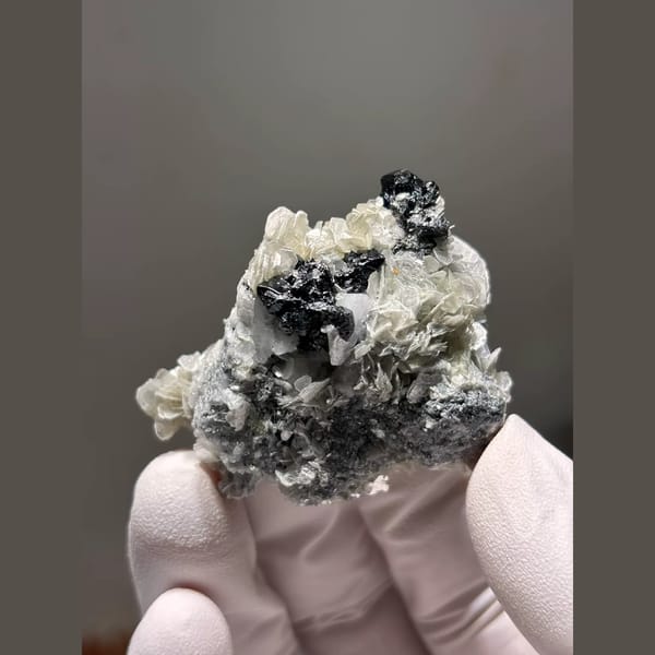 Black cassiterite with mica and feldspar from Xuebaoding, Sichuan — alternate view