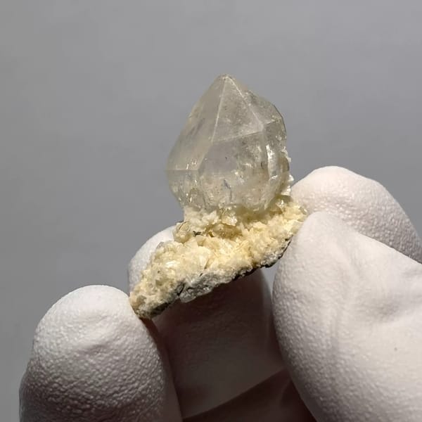 Clear Quartz Point on White Matrix from Yunnan, China, held in a gloved hand, photo 1 of 3