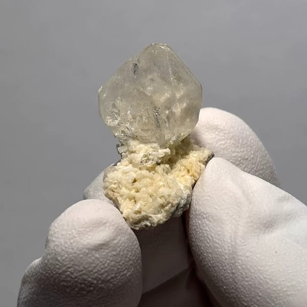 Clear Quartz Point on White Matrix from Yunnan, China, held in a gloved hand, photo 2 of 3