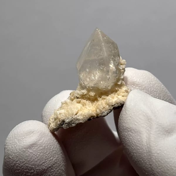 Clear Quartz Point on White Matrix from Yunnan, China, held in a gloved hand, photo 3 of 3