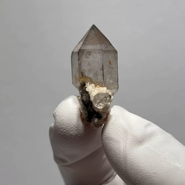 Yunnan quartz point with sketch-like inclusions and matrix base — detail view