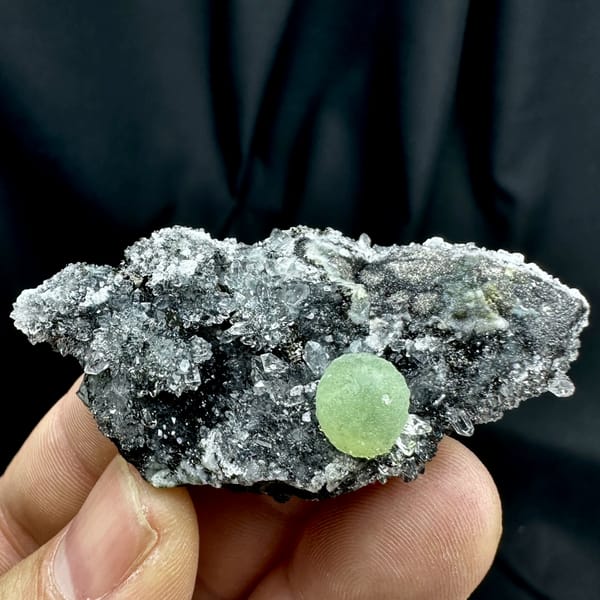Green prehnite ball on black matrix with white quartz druse from Sichuan, China, second angle