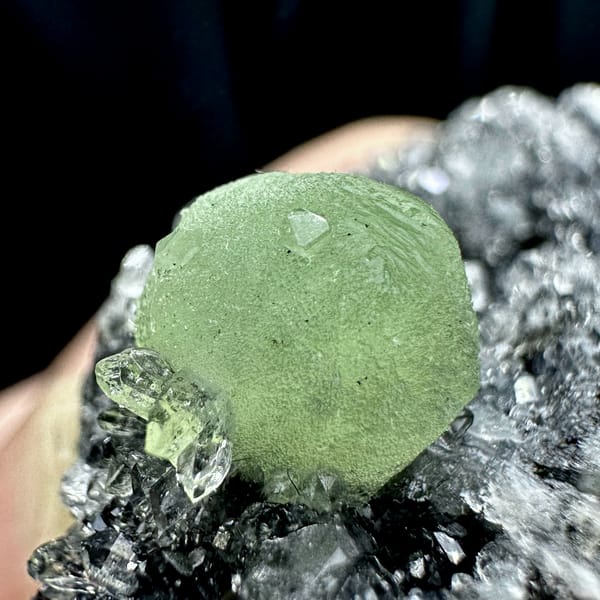 Green prehnite ball on black matrix with white quartz druse from Sichuan, China, reverse side