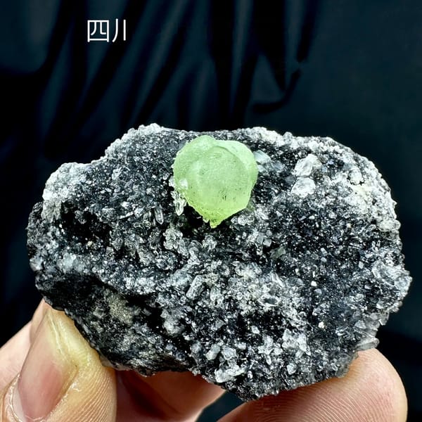 Apple-green prehnite sphere on dark matrix coated in quartz druse from Sichuan, China