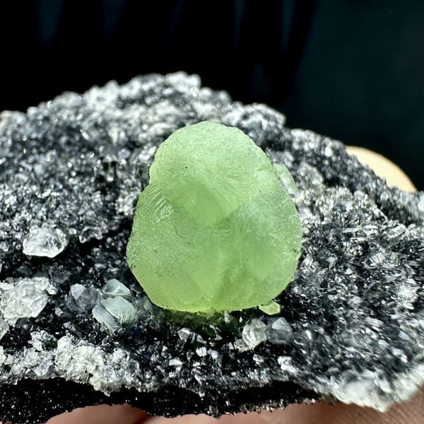 Apple-green prehnite sphere on dark matrix coated in quartz druse from Sichuan, China, second angle