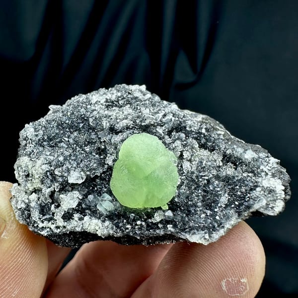 Apple-green prehnite sphere on dark matrix coated in quartz druse from Sichuan, China, reverse side