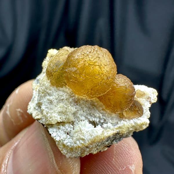 Two amber-yellow botryoidal fluorite balls on white quartz from Henan, China, close-up of the crystal faces