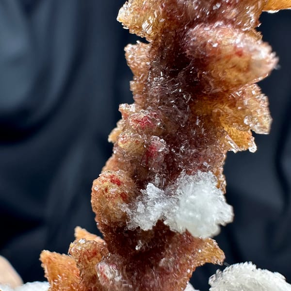Rust-red double-terminated calcite crystal enclosed in white gypsum from Guizhou, China, close-up of the crystal faces