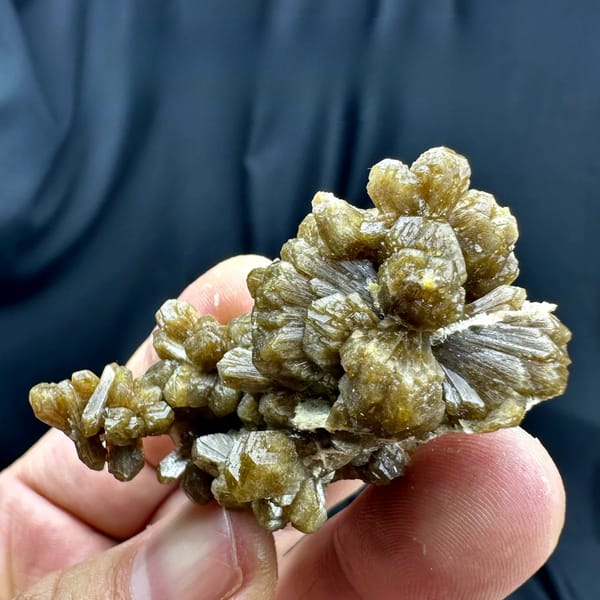 Golden-brown bow-tie stilbite crystal cluster from Yunxiao, Fujian, China, held in hand
