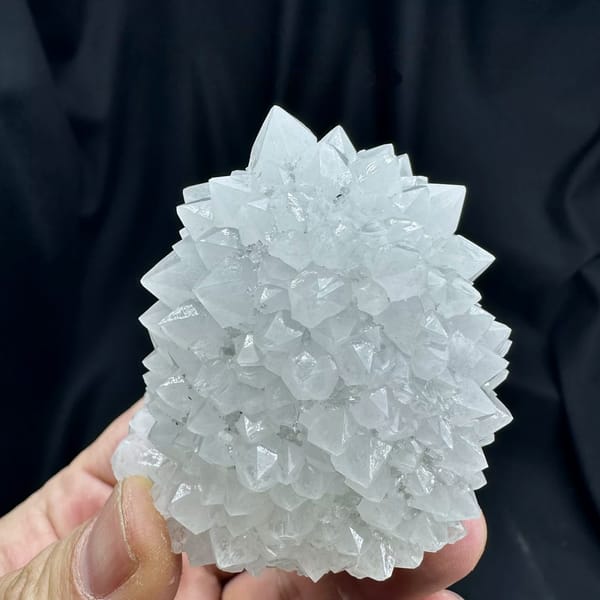 Dome of pale quartz points with green fluorite from Guangdong, China, held in hand