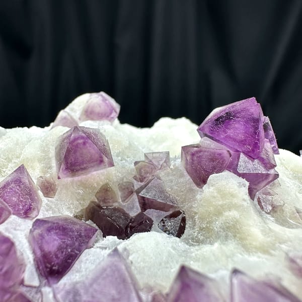 Purple fluorite octahedra on white quartz plate from Zhejiang, China, close-up of the crystal faces