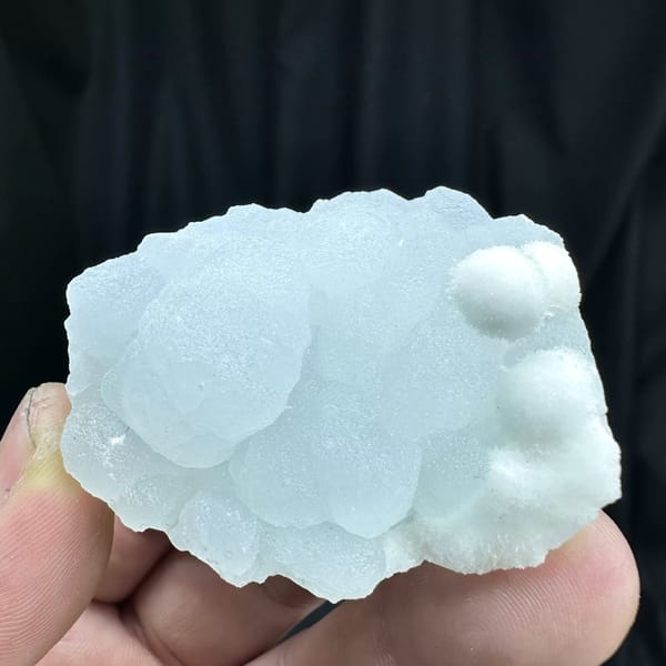 Powder-blue botryoidal aragonite with white aragonite from Yunnan, China, held in hand