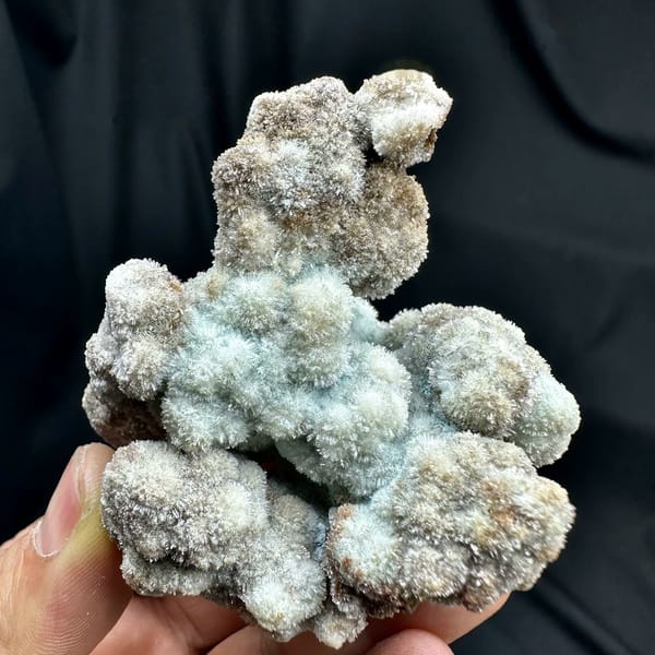 Blue-grey botryoidal creedite floater from Guizhou, China, held in hand